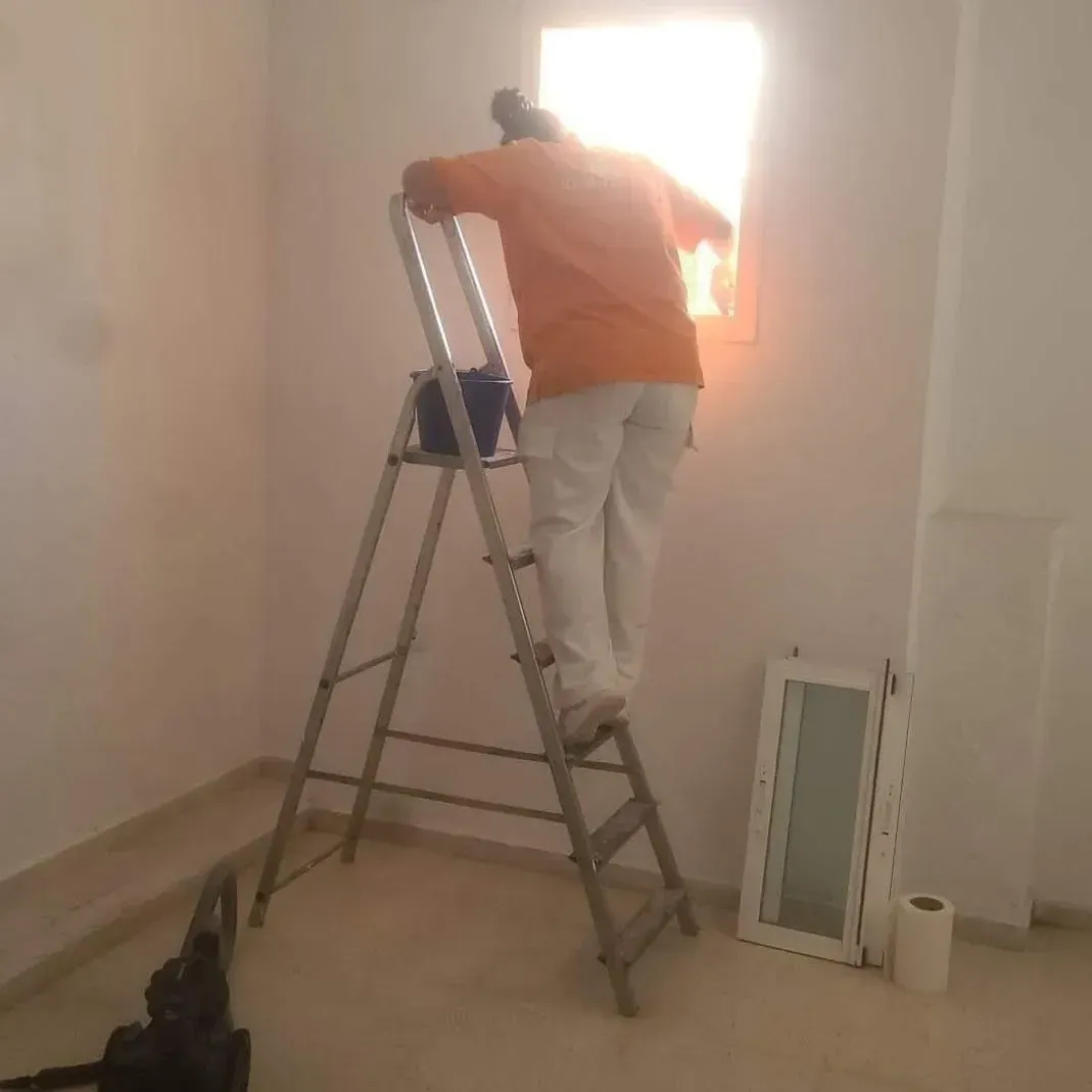 Un hombre está de pie en una escalera frente a una ventana.