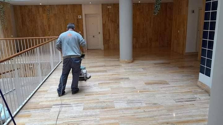 Un hombre está limpiando un piso de madera con una máquina.
