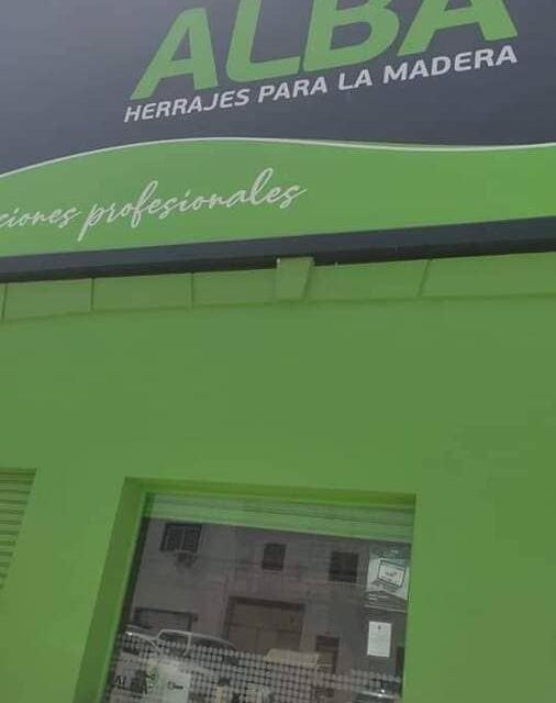 Un edificio verde con un cartel que dice alba herrajes para la madera