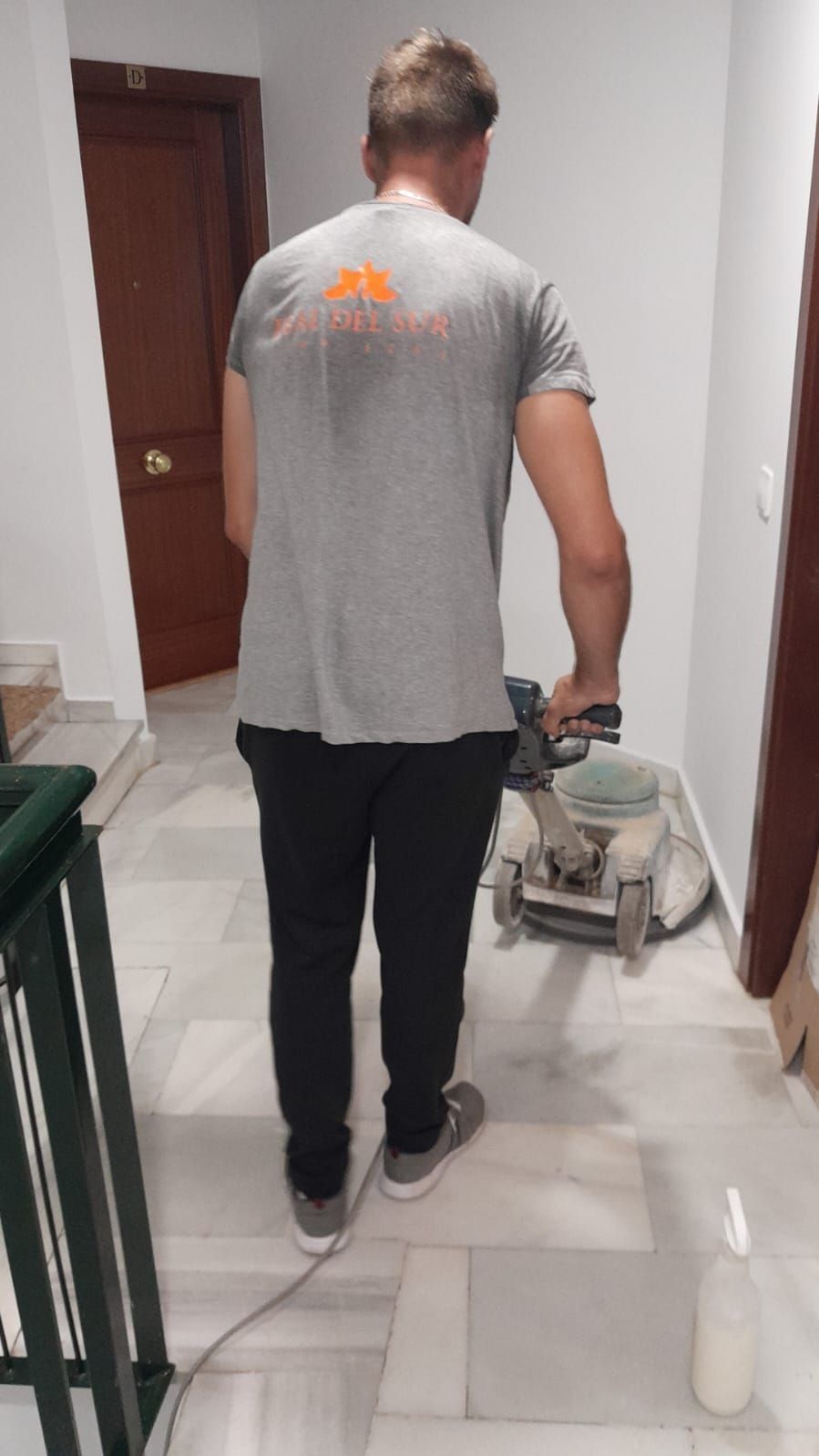 Un hombre está limpiando un piso de baldosas con una máquina.