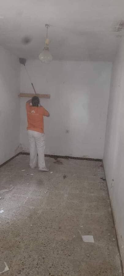 Un hombre está parado en una habitación vacía con una escoba.