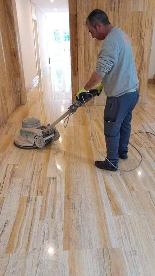 Un hombre está puliendo un piso de mármol con una máquina.