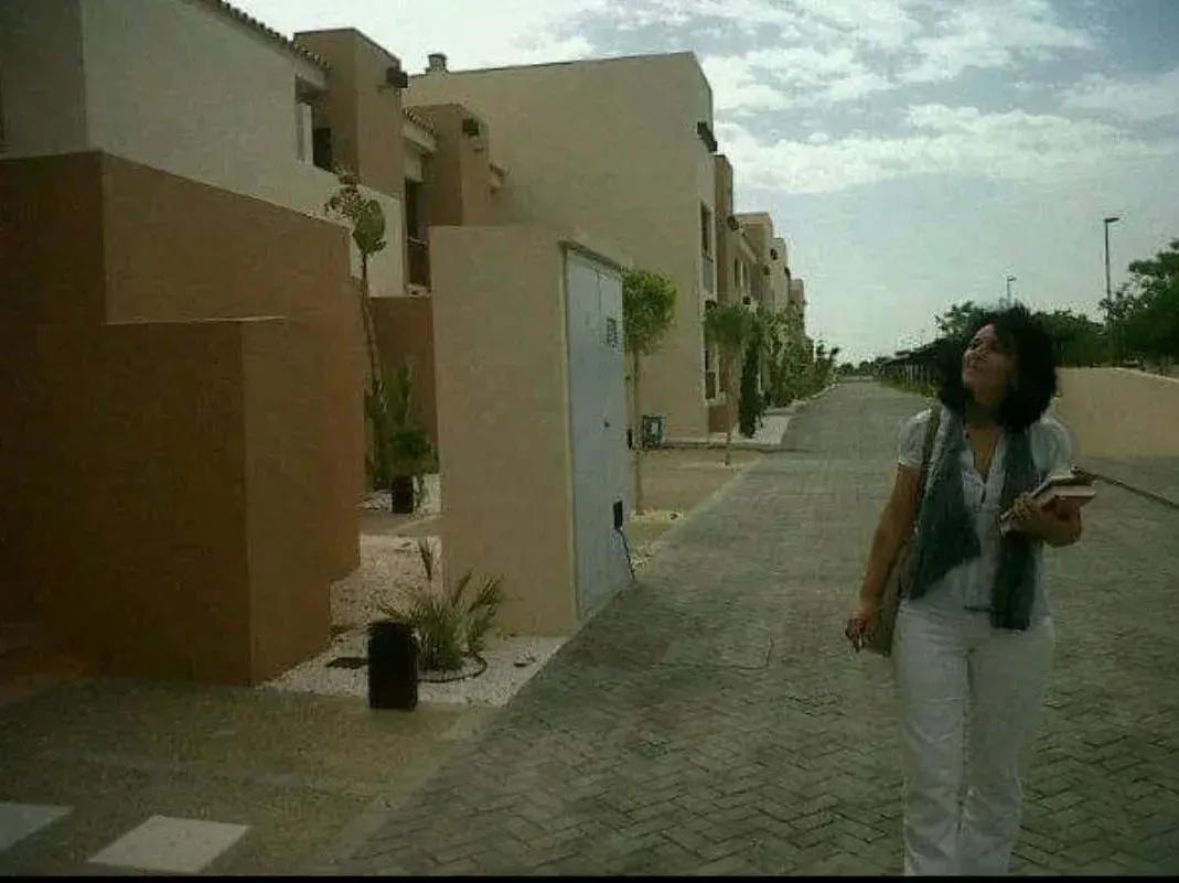 Una mujer camina por una calle frente a un edificio.