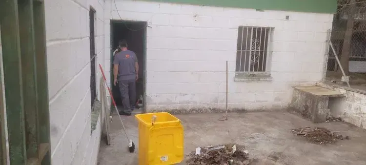 Un hombre está parado en una puerta al lado de un bote de basura amarillo.