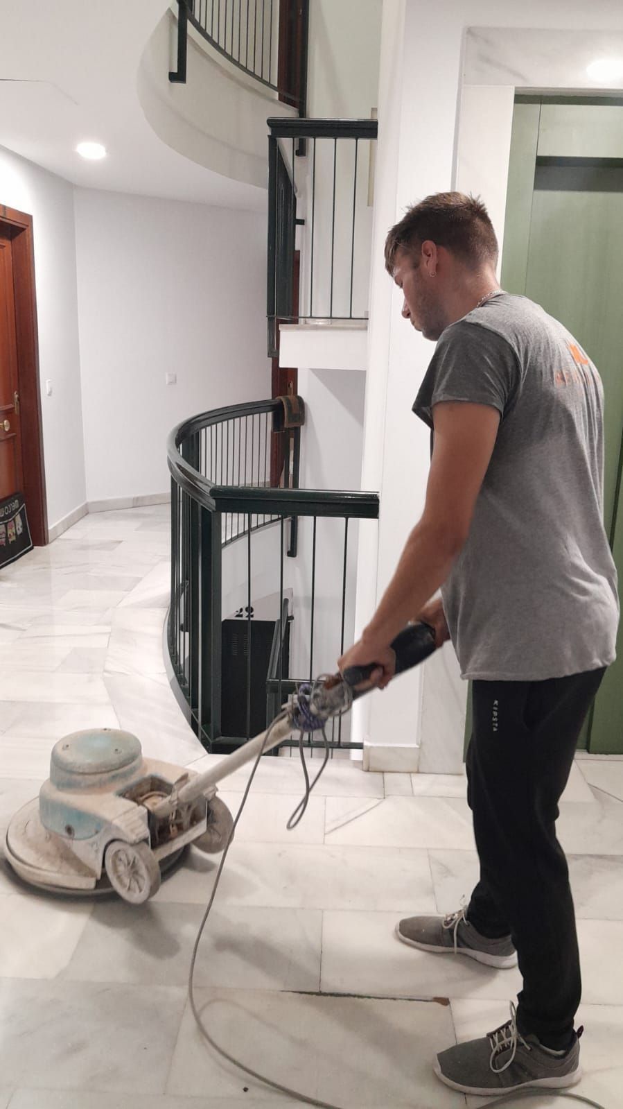 Un hombre está usando una máquina para pulir un piso de baldosas.