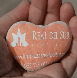 Una persona sostiene una roca en forma de corazón que dice real del sur