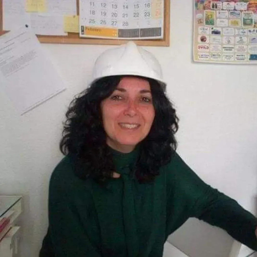Una mujer que lleva un casco sonríe delante de un calendario.