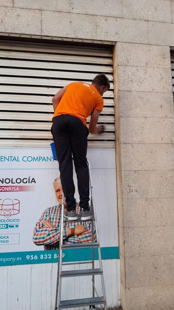 Un hombre está de pie en una escalera limpiando una ventana.