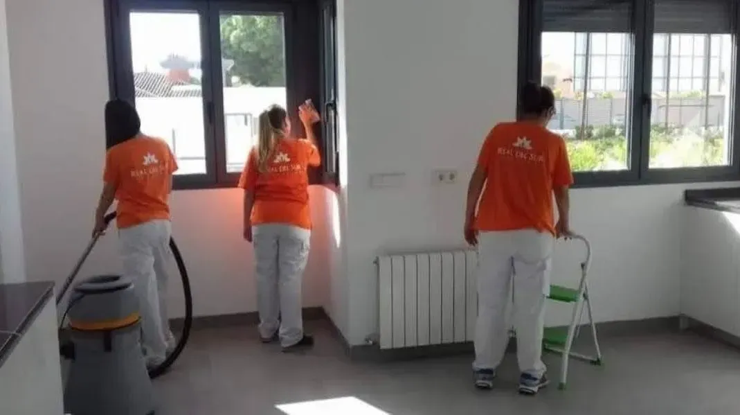 Un grupo de personas está limpiando una habitación con una aspiradora.