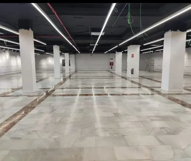 Una gran habitación vacía con columnas y luces en el techo.