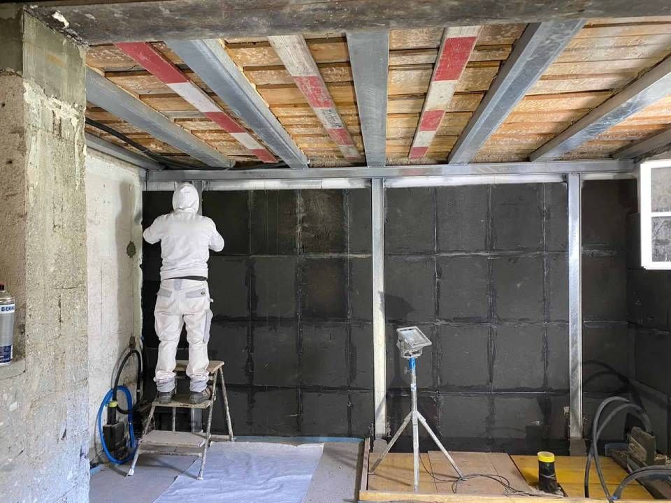 Ein Handwerker steht auf einem Hocker in einem Raum. Foto von der H. Kuhn Hoch- und Tiefbau AG