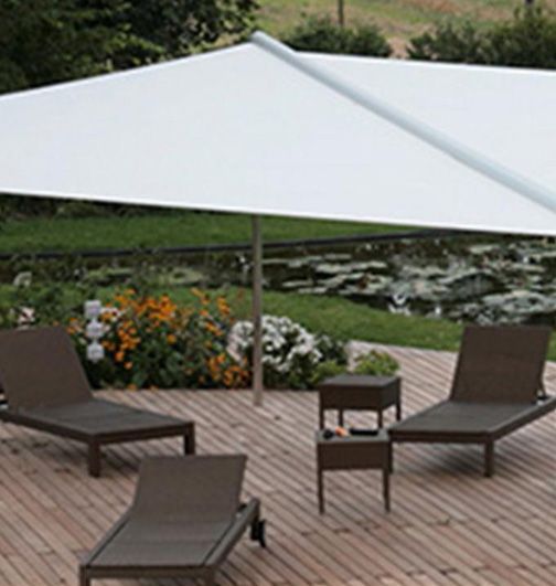 Una terraza de madera con sillas y mesas bajo una sombrilla.