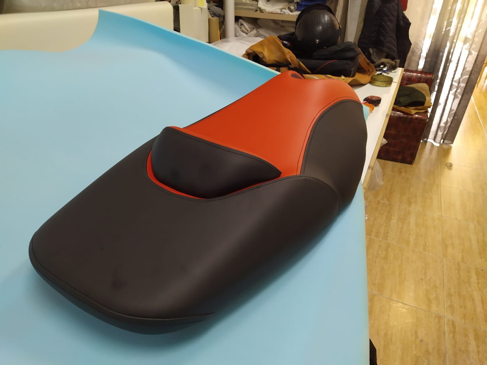 Un asiento de motocicleta negro y rojo está sobre una mesa.
