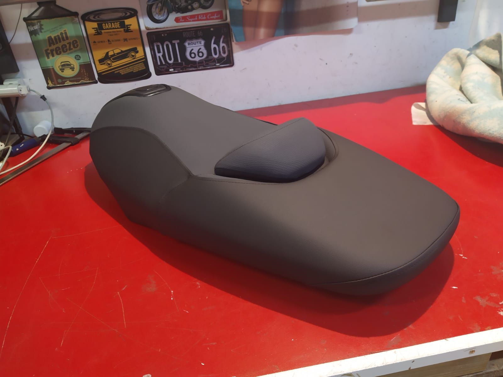 Un asiento de motocicleta está sobre una mesa roja.