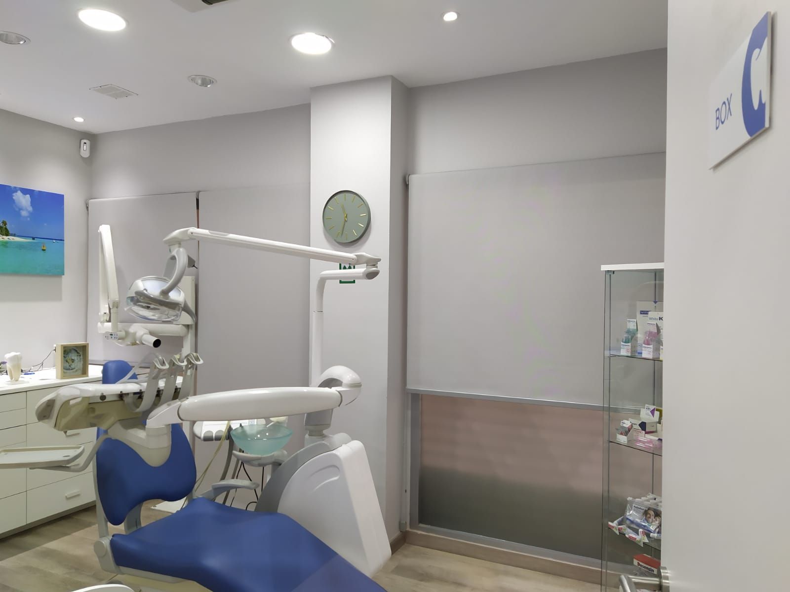 Un consultorio dental con una silla azul y un reloj en la pared.