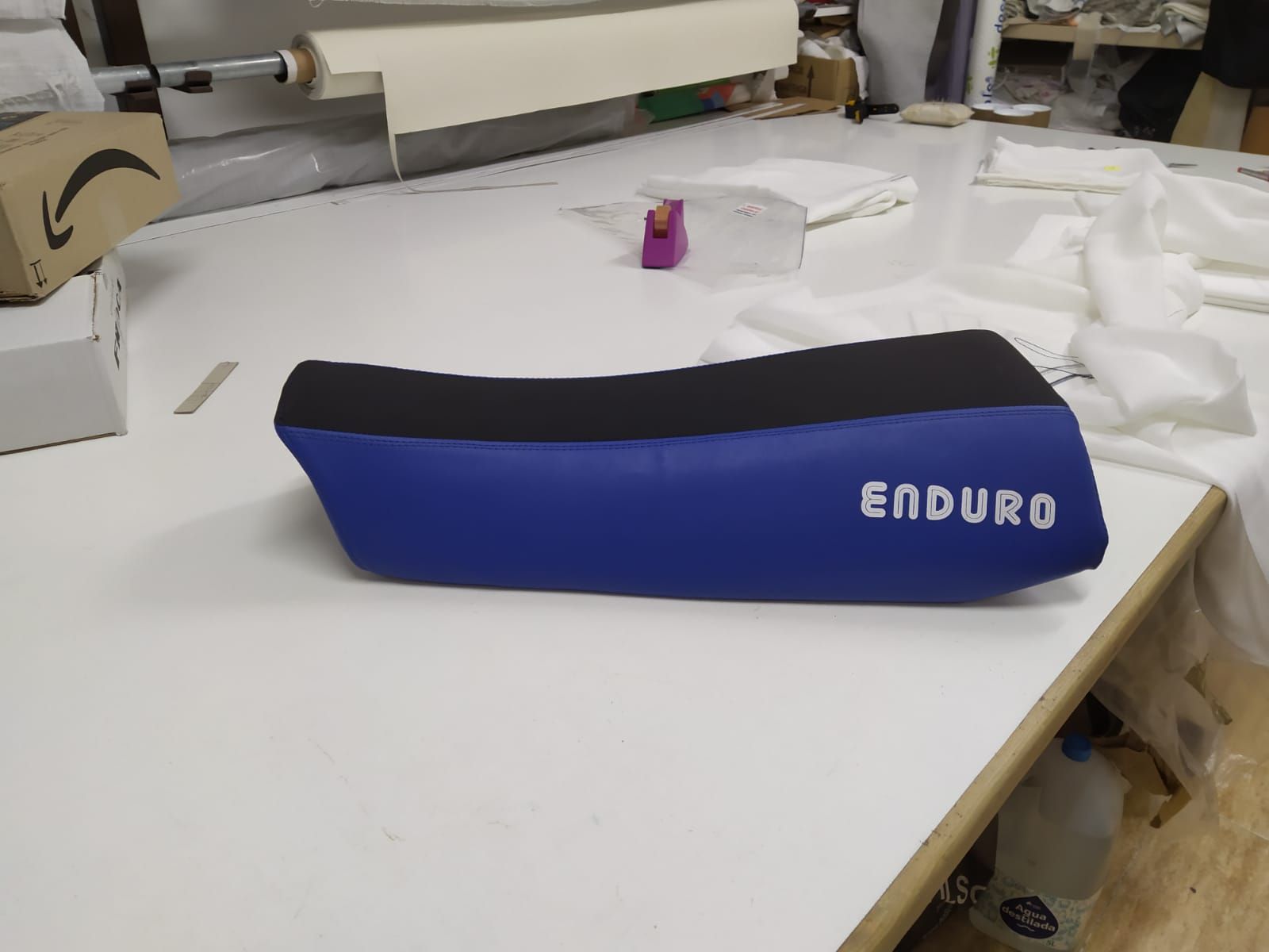 Un asiento de enduro azul y negro se encuentra sobre una mesa blanca.