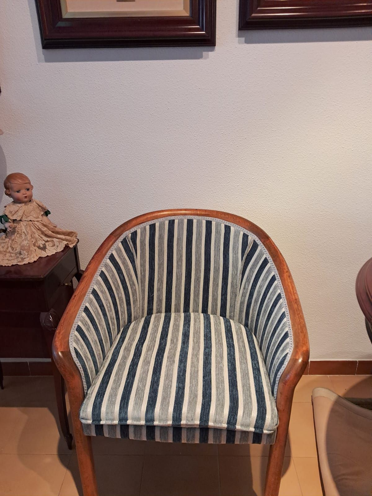 Una silla a rayas con estructura de madera se encuentra en una sala de estar.