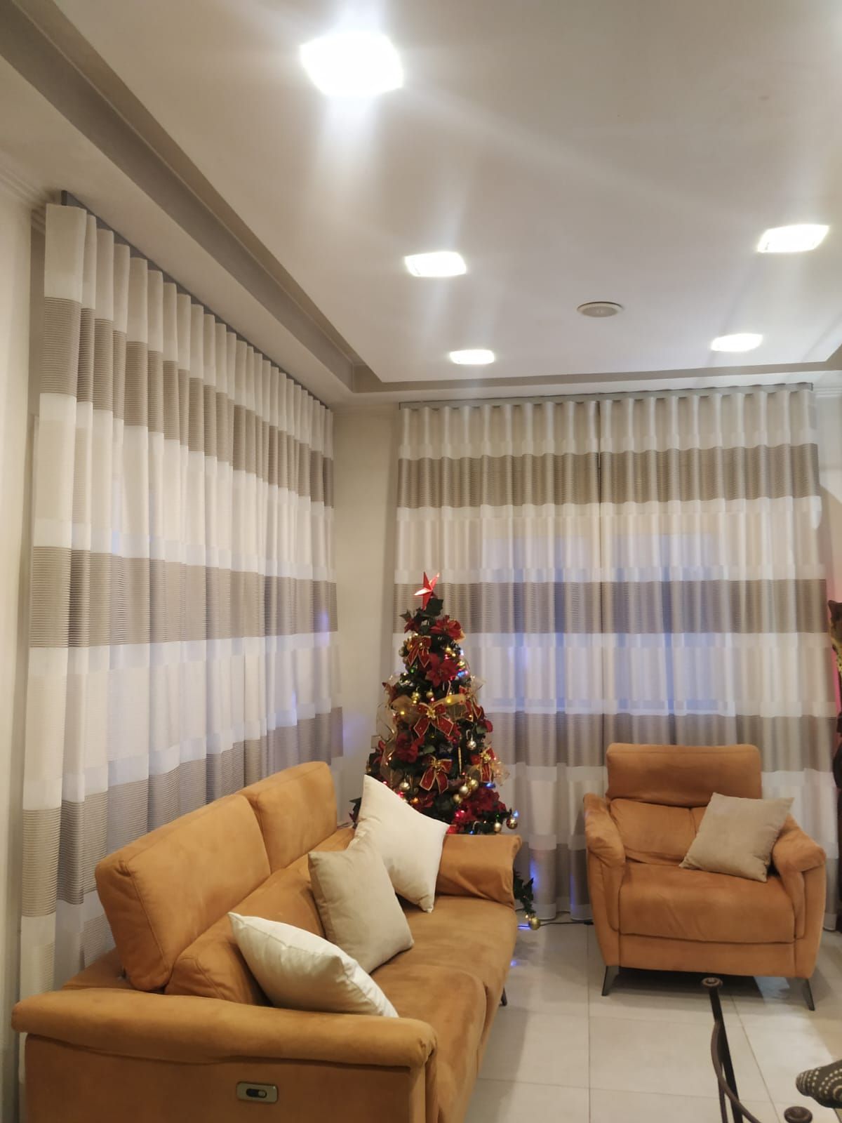 Una sala de estar con un sofá, una silla y un árbol de Navidad.