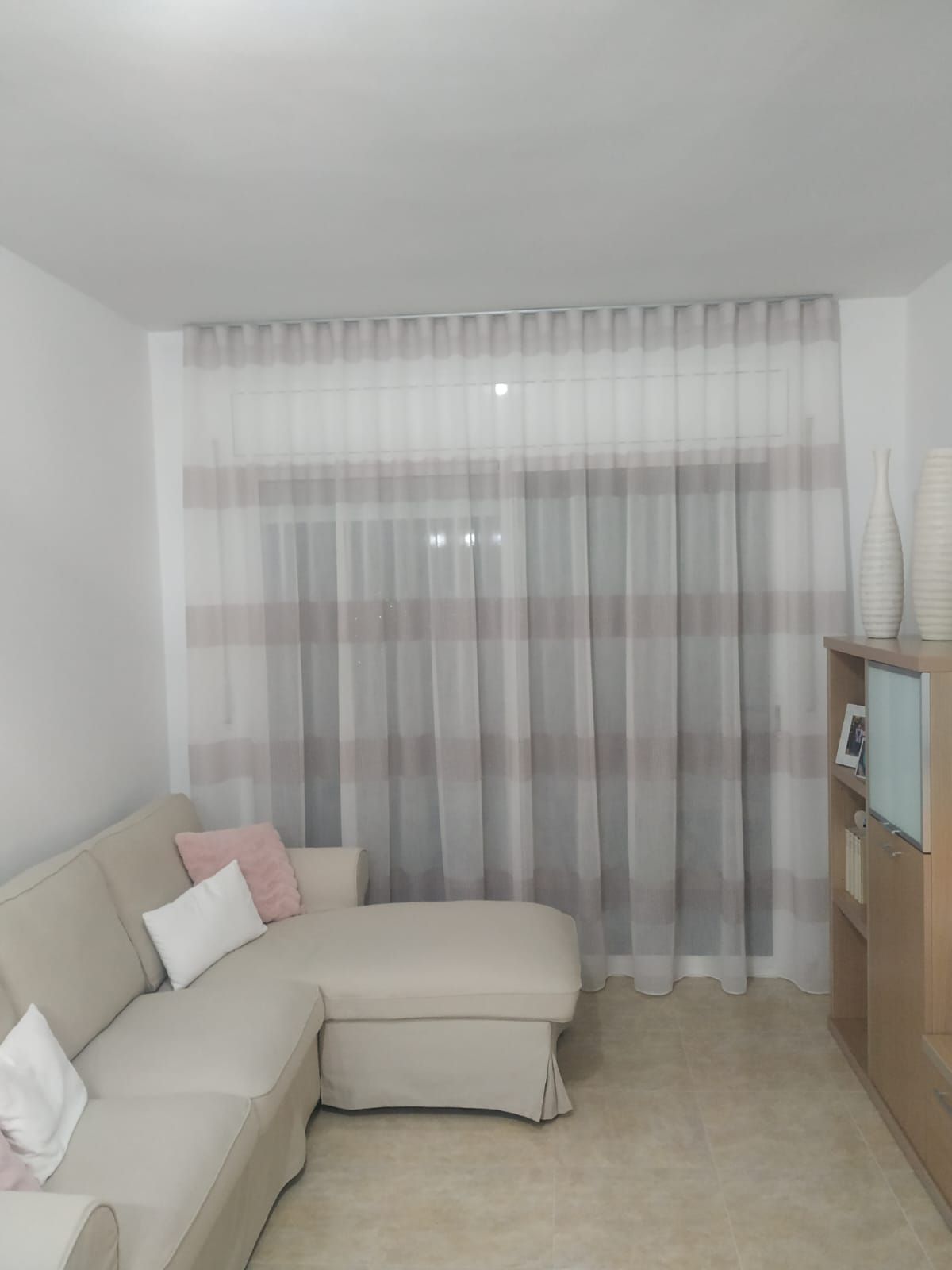 Una sala de estar con un sofá seccional y cortinas.