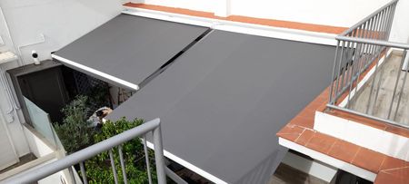 Vista superior que muestra dos toldos grises que cubren un balcón.