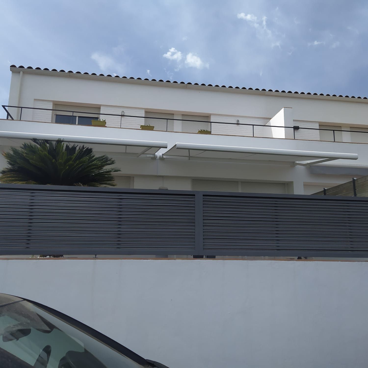 Un edificio blanco con una valla negra delante.