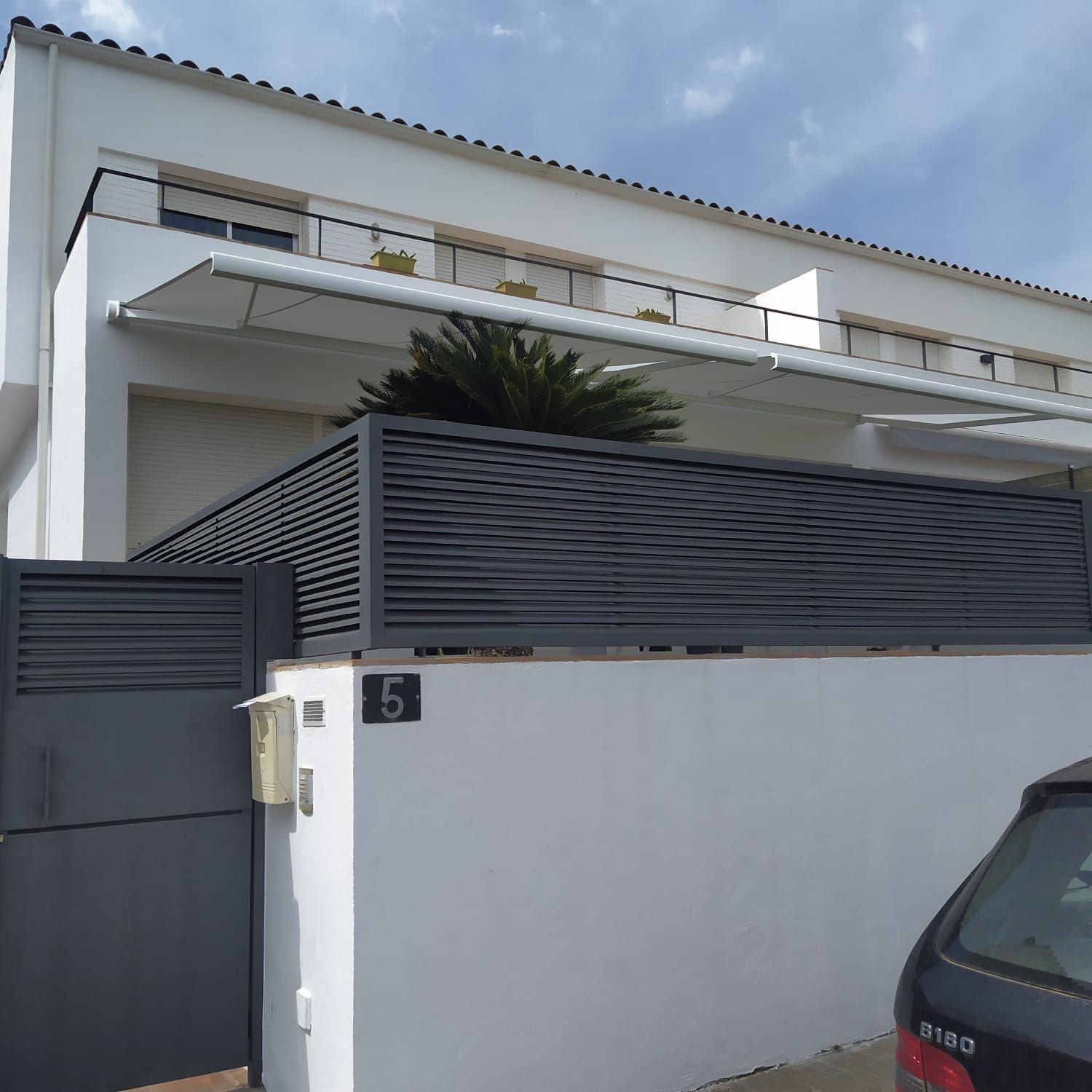 Un coche está aparcado delante de una casa con el número 6.