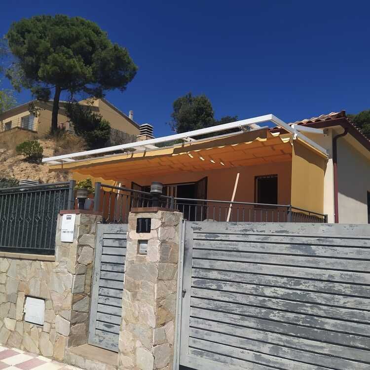 Una casa con una valla de madera y un dosel en el techo.