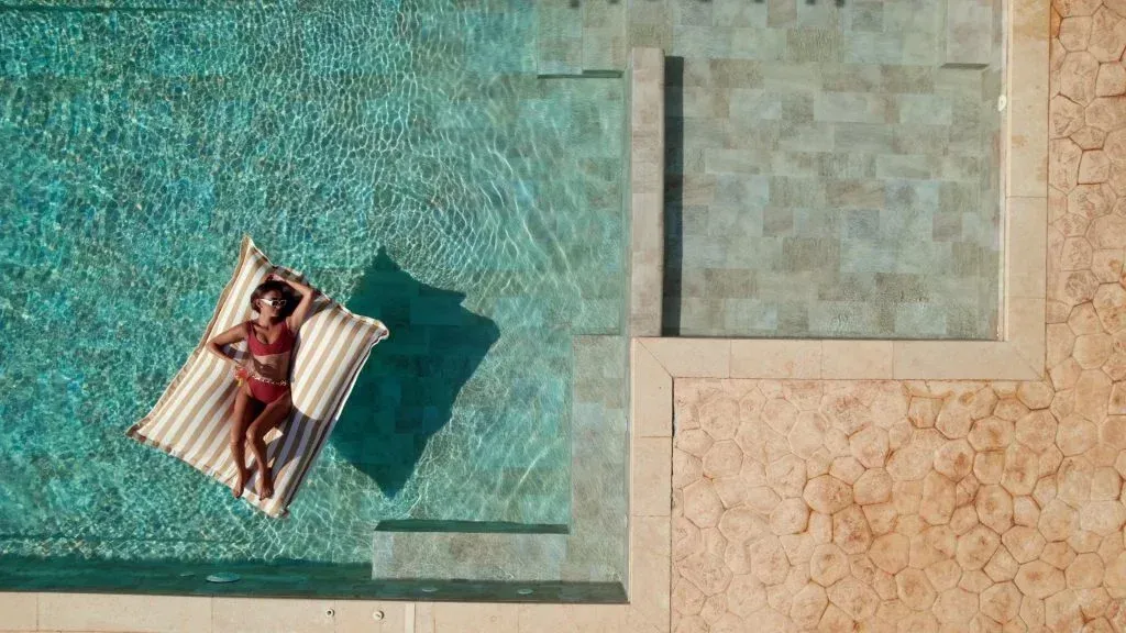 Piscine avec une femme sur un matelas.