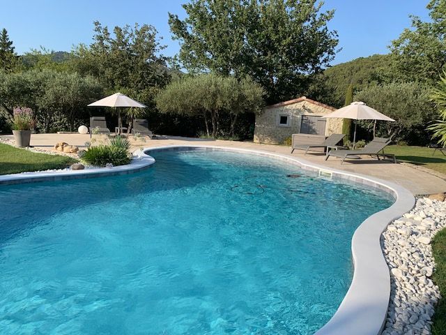 Piscine d'un particulier arboré avec des transats.