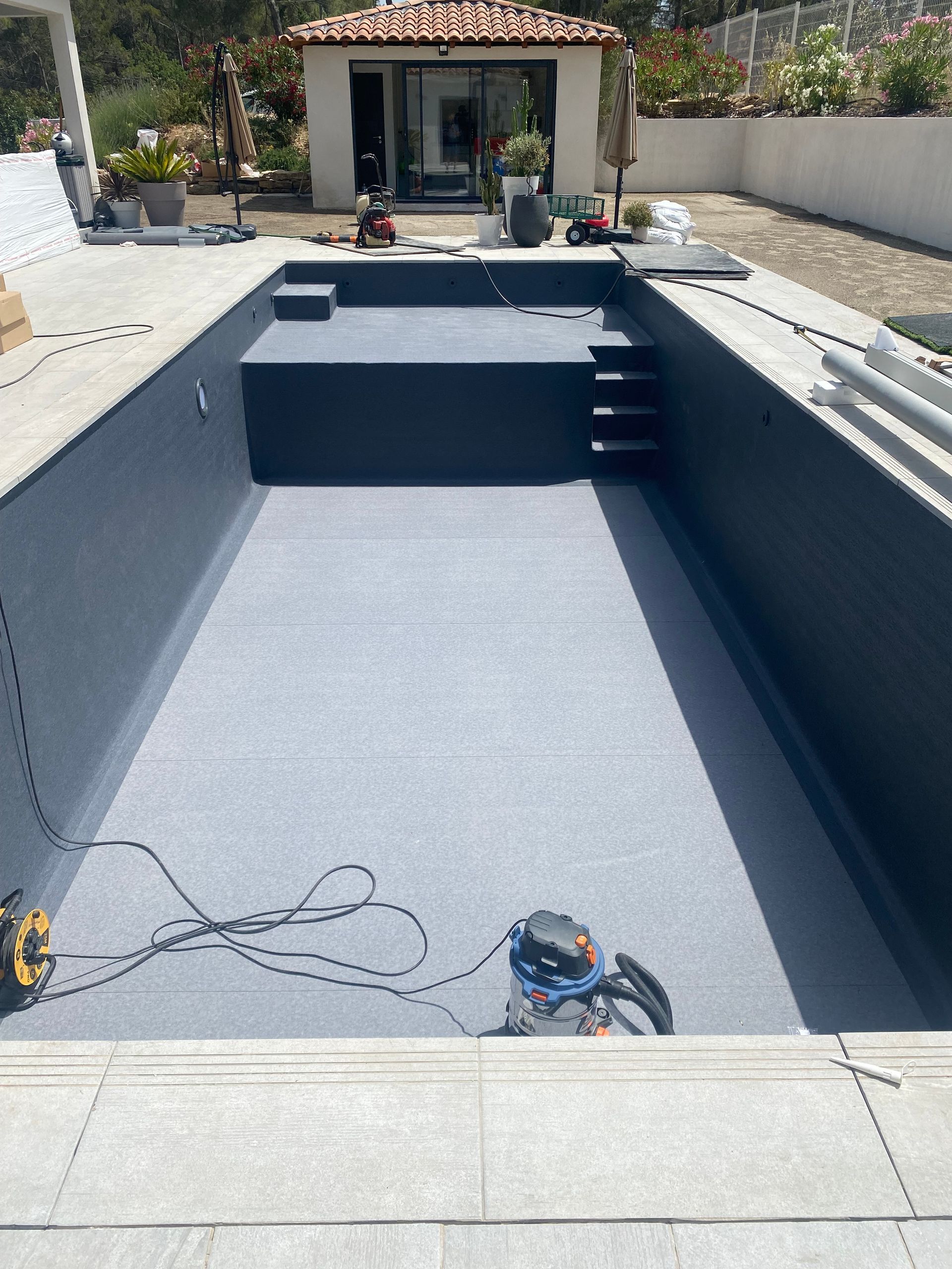 Installation d'une membrane de couleur grise dans une piscine.