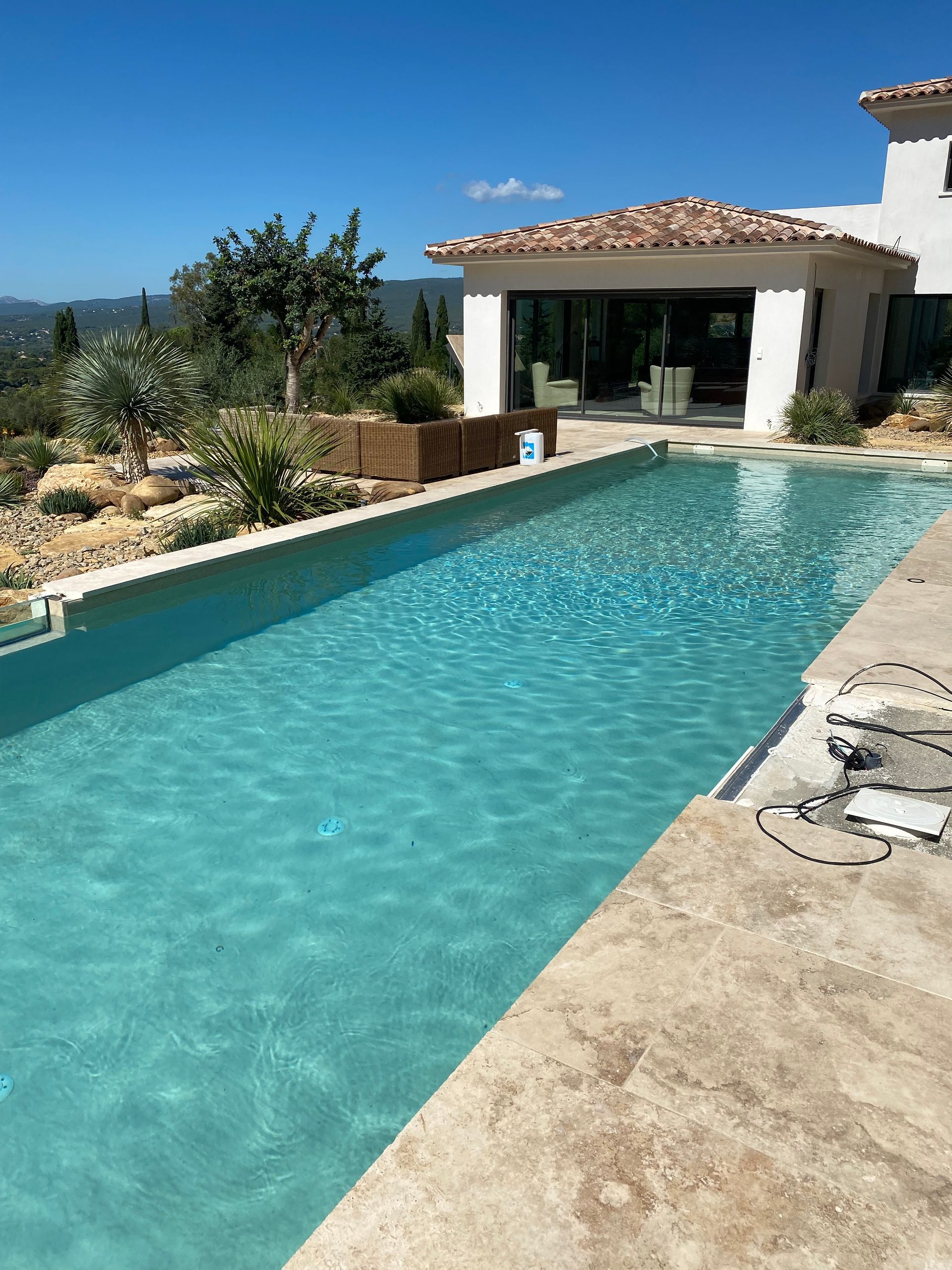 Une longue piscine bleu dans un jardin.