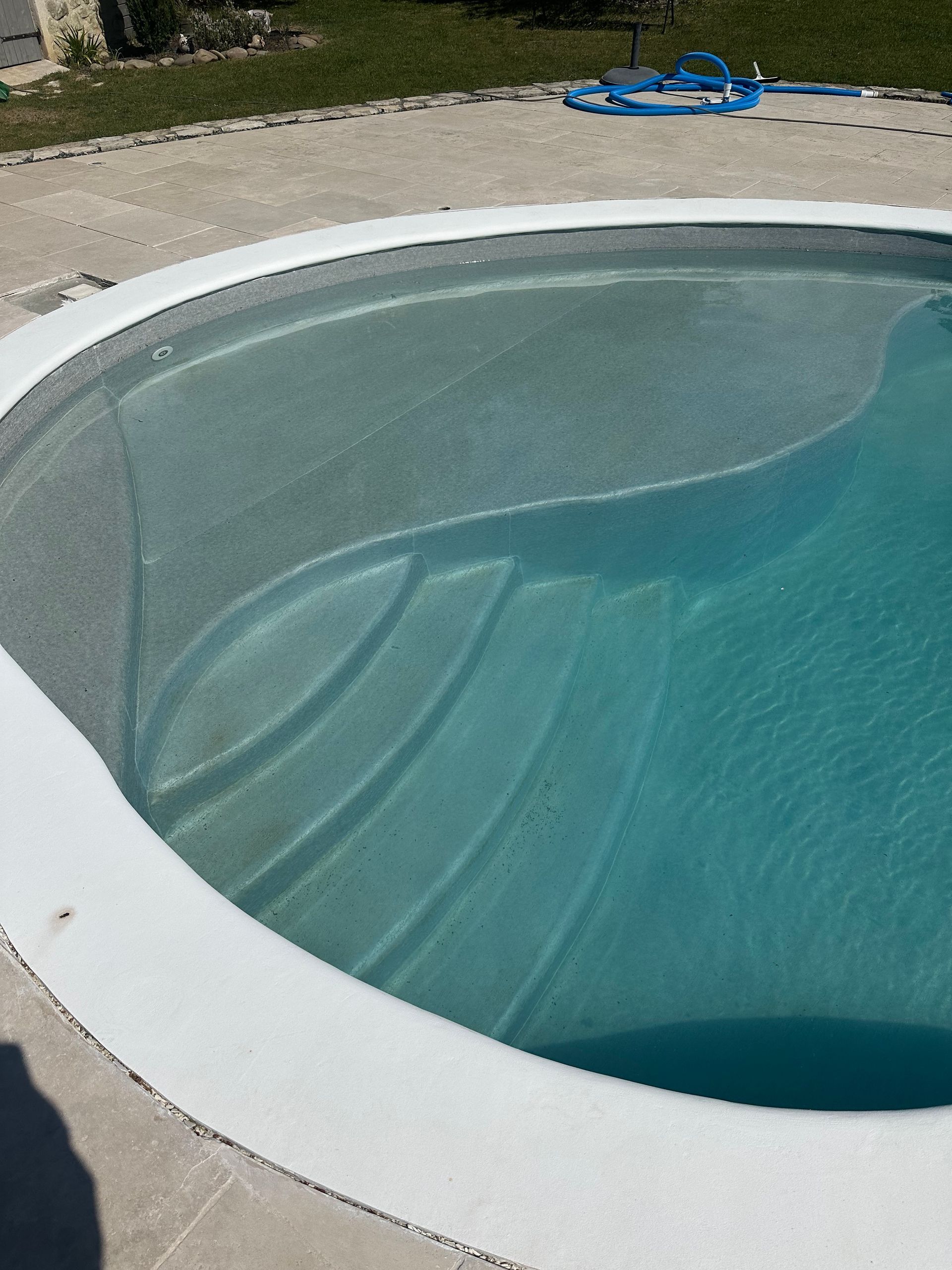 Un escalier de piscine arrondie remplie d'eau.