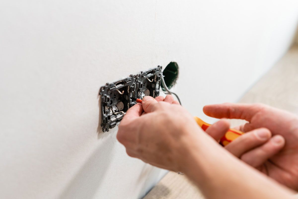 Una persona está instalando una toma de corriente eléctrica en una pared.