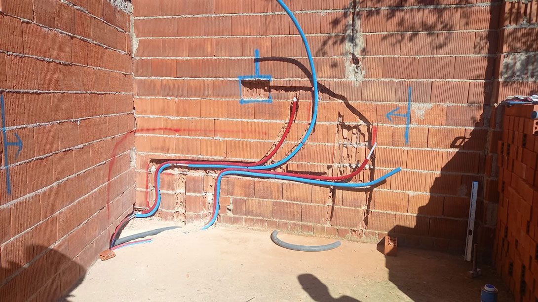 Una pared de ladrillos con un montón de tuberías saliendo de ella.