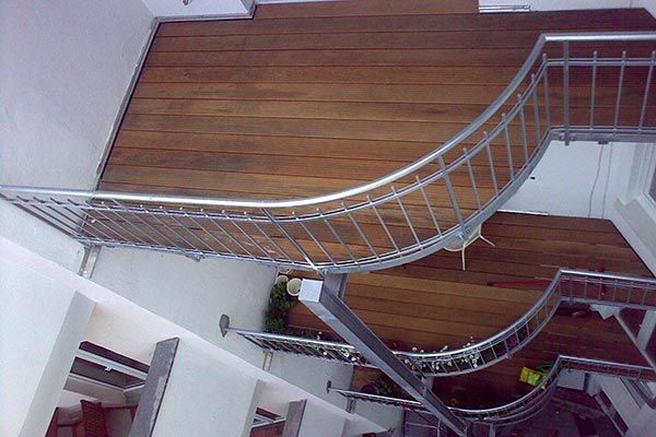 Eine geschwungene Treppe mit Metallgeländer, Holzstufen und weißen Wänden.