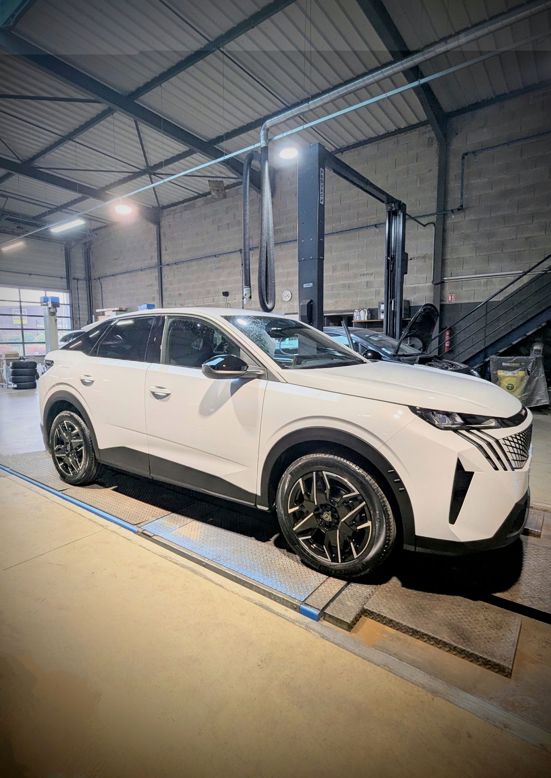 Intérieur d'un garage automobile avec une voiture blanche.