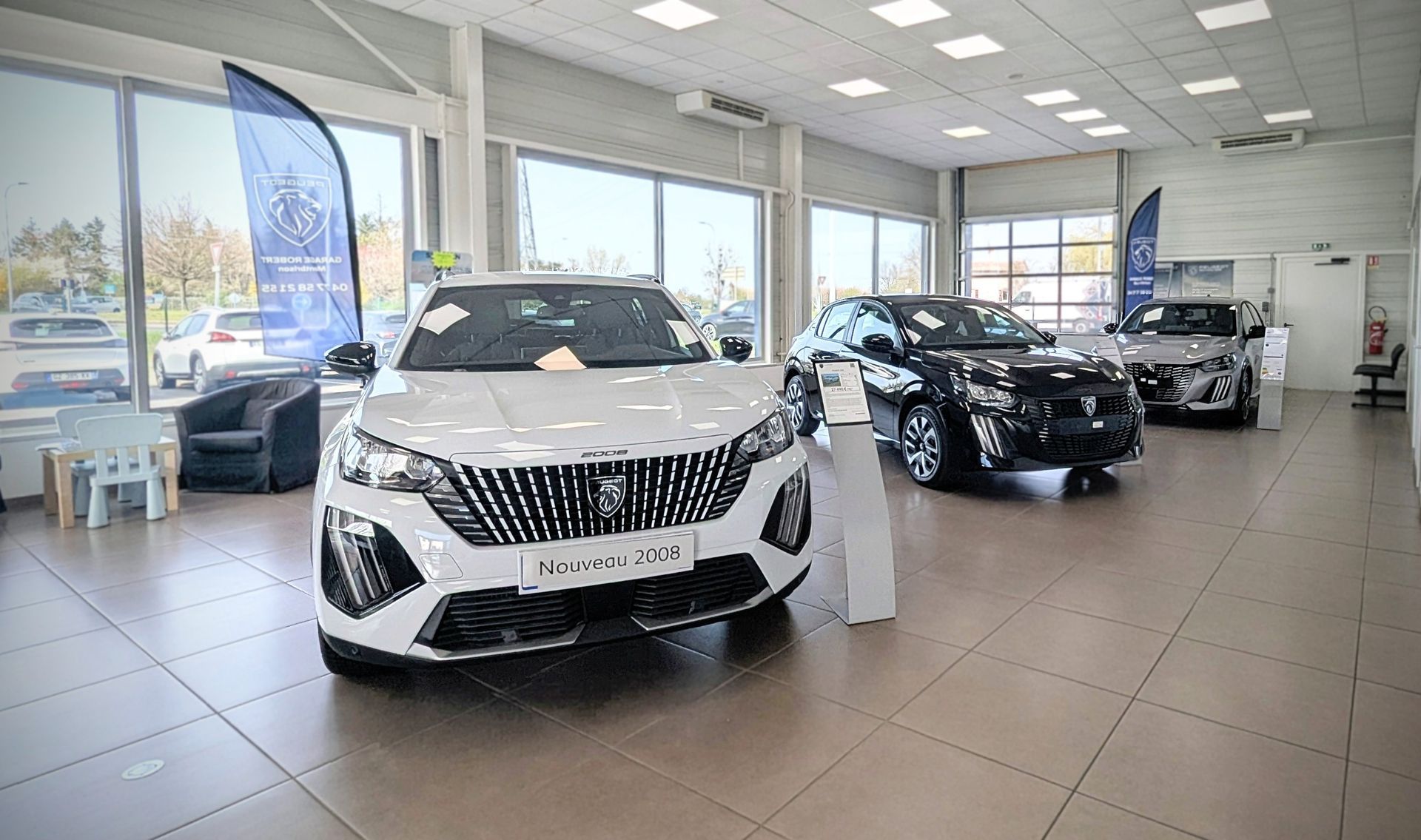 Véhicules blancs et noirs exposés dans un garage automobile Peugeot.