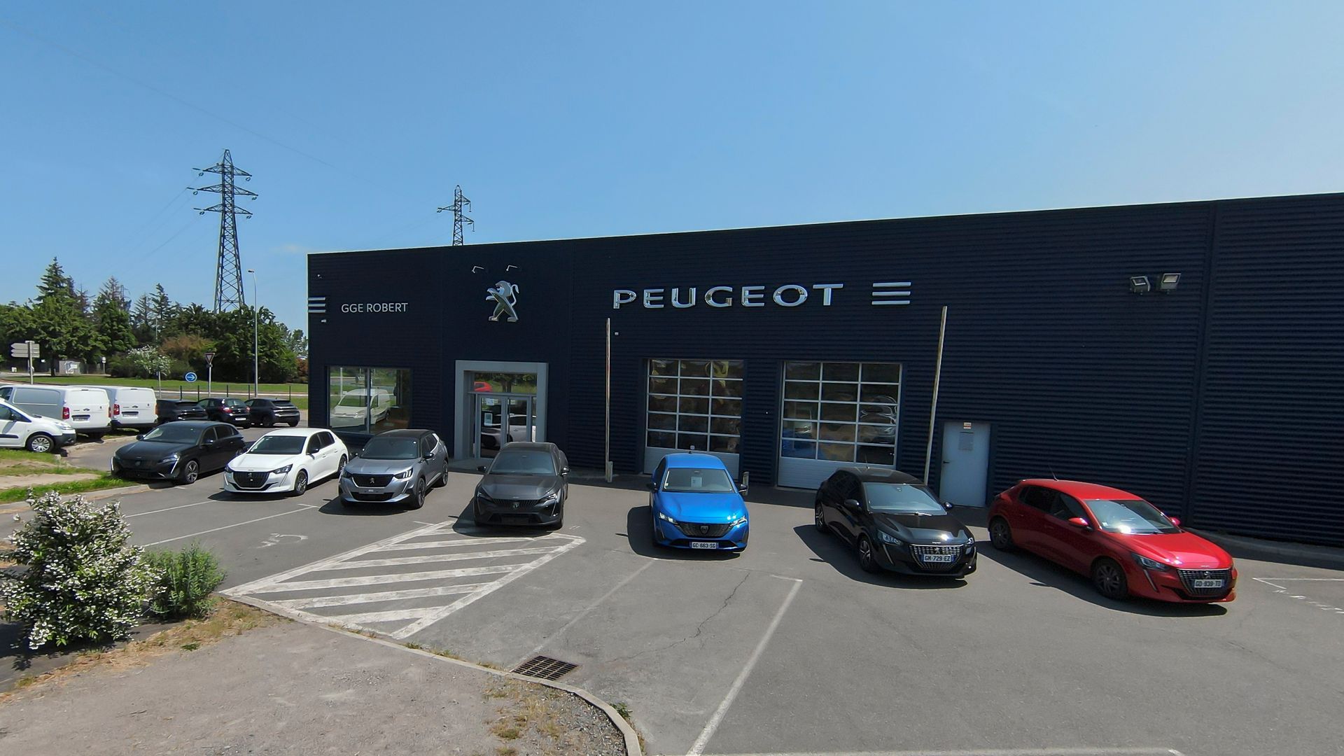 Devanture du garage Peugeot Robert avec plusieurs véhicules stationnés devant.