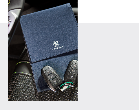 Clés et pochette Peugeot sur un siège de voiture.