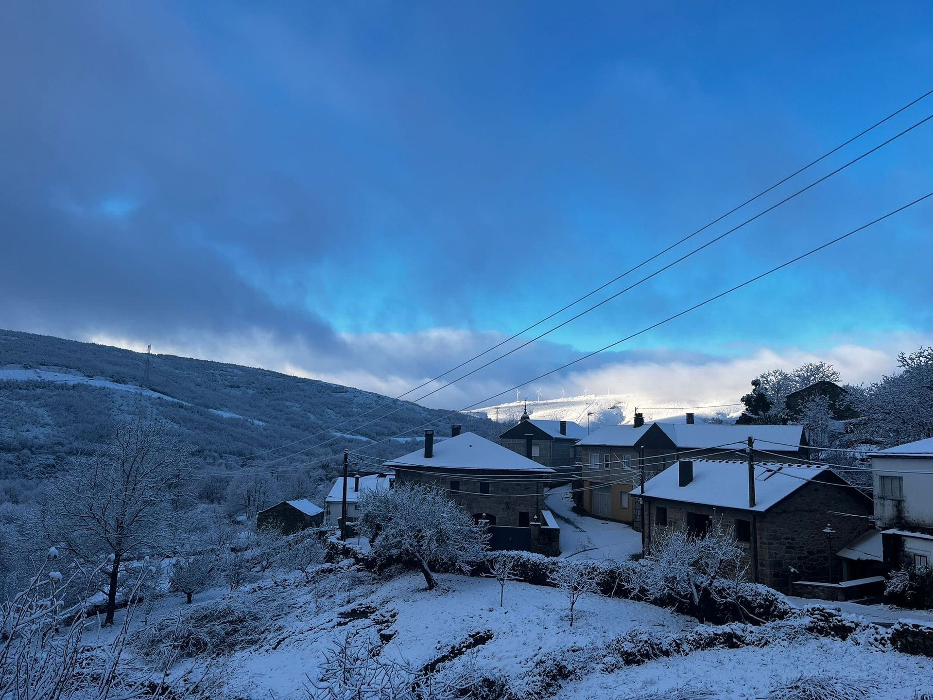 Pueblo cubierto de nieve situado en un valle de montaña bajo un cielo azul parcialmente nublado.
