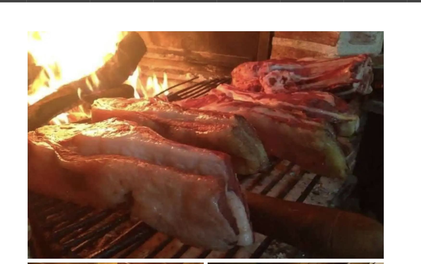 Grandes trozos de carne asándose sobre fuego abierto.