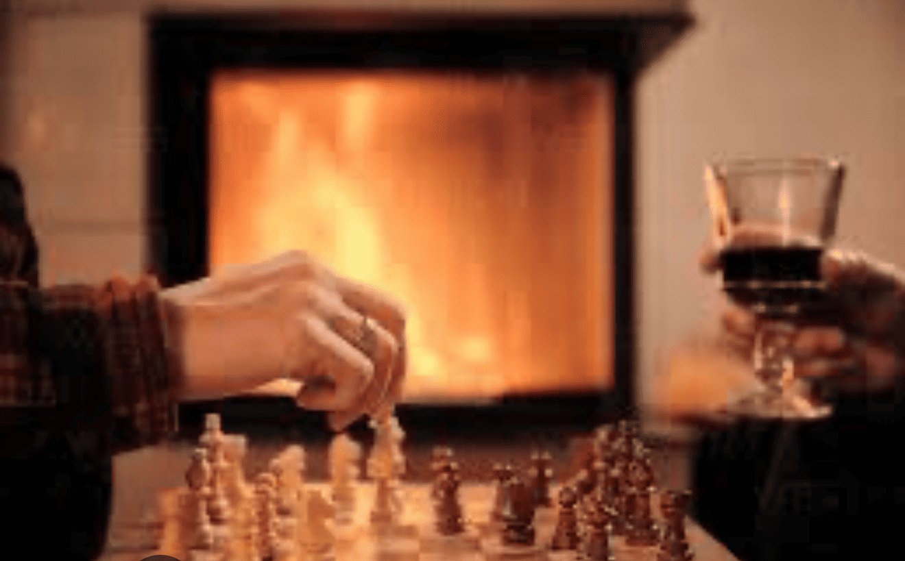 Manos moviendo piezas de ajedrez, otra sosteniendo una copa de vino, fuego en el fondo.