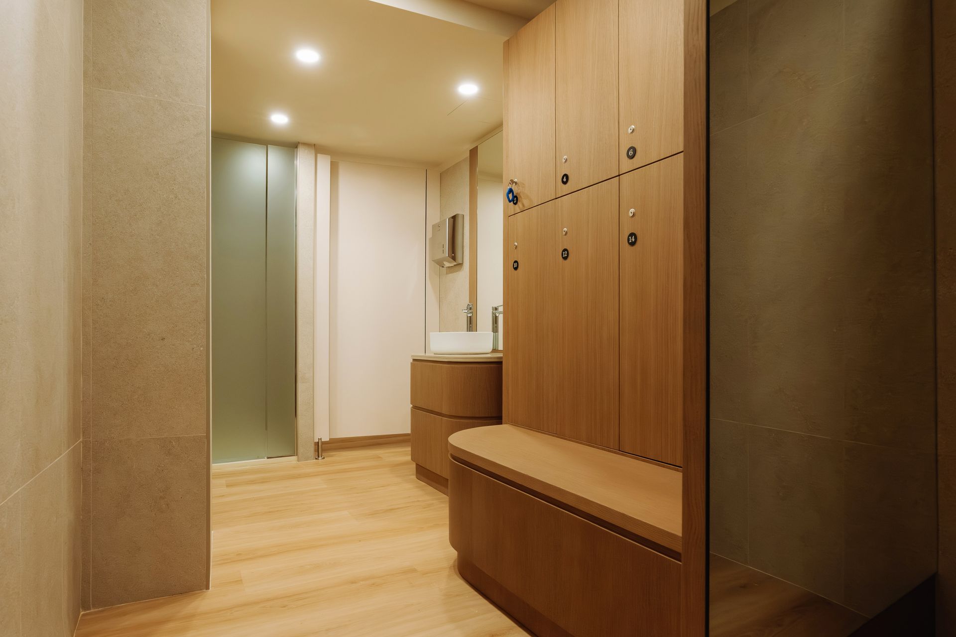 Pasillo moderno con armarios de madera, bancos y suelo de madera clara en un interior minimalista.