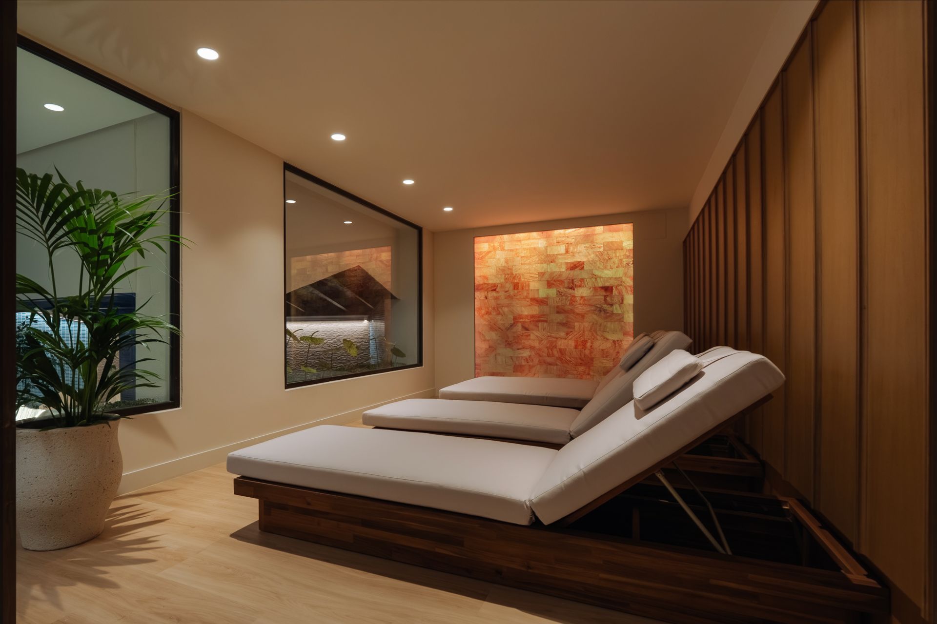 Sala de spa moderna con camilla de masaje, iluminación cálida, paneles de madera y obras de arte en las paredes.