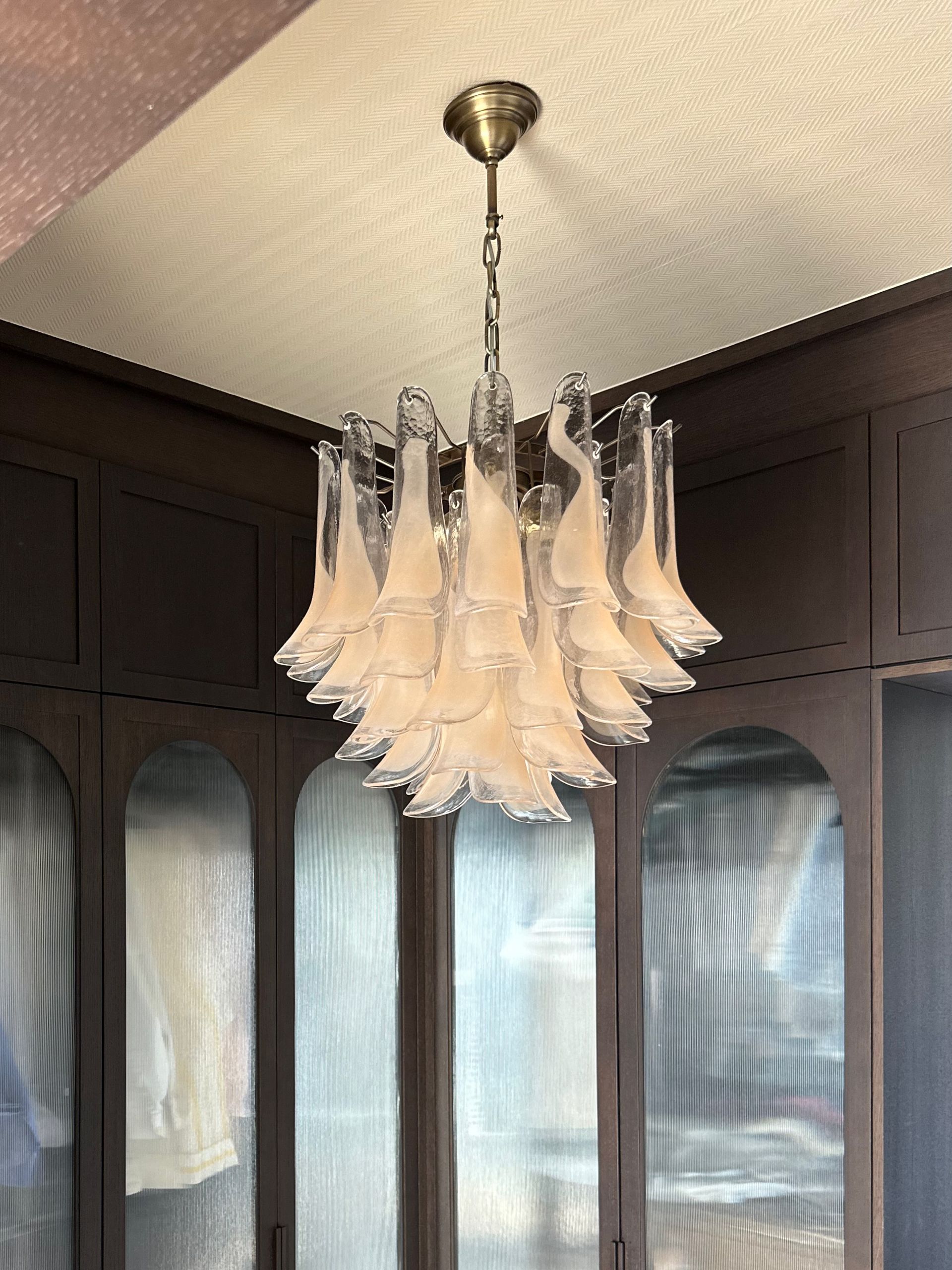 Lámpara de araña moderna con colgantes de cristal en una habitación con paneles oscuros.