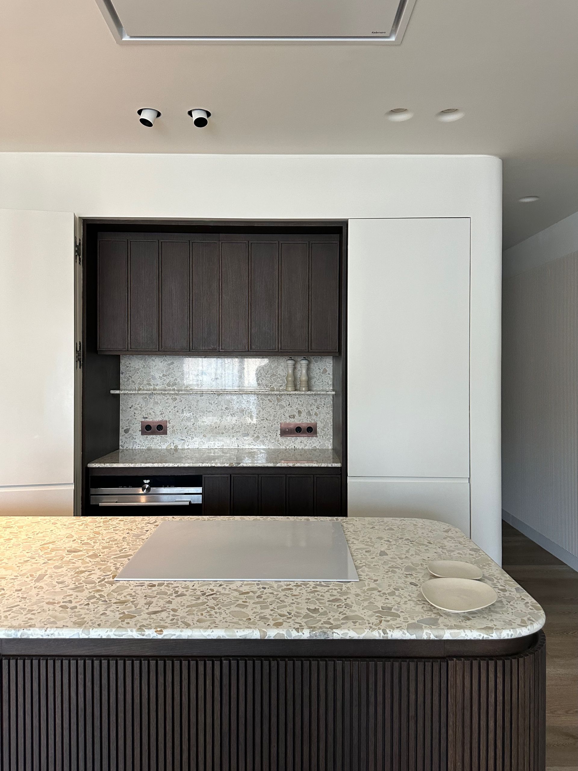 Cocina moderna con gabinetes oscuros, salpicadero de mosaico y encimera de isla de granito.