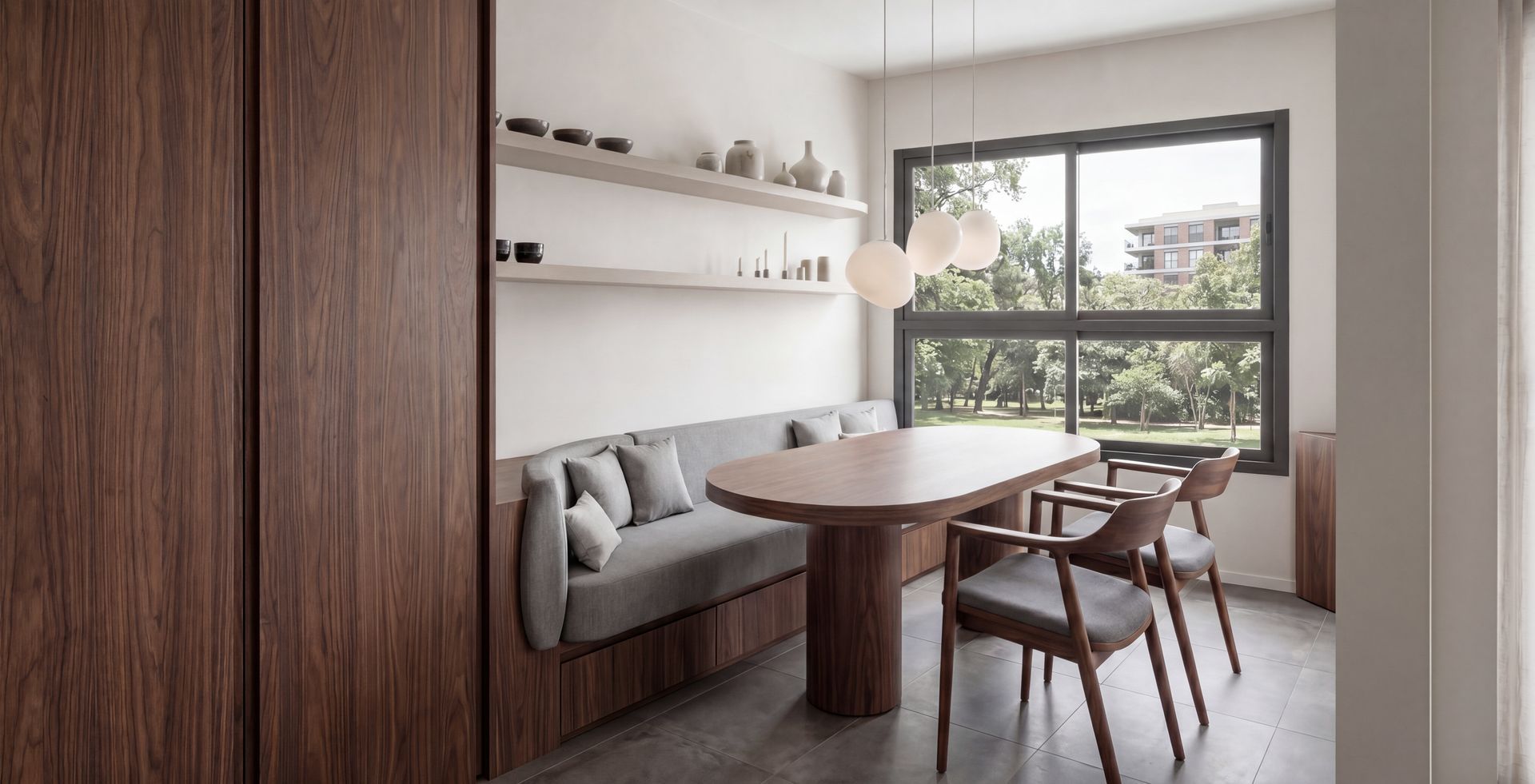 Rincón de comedor moderno con mesa de madera, banco acolchado, sillas, lámparas colgantes y una gran ventana.