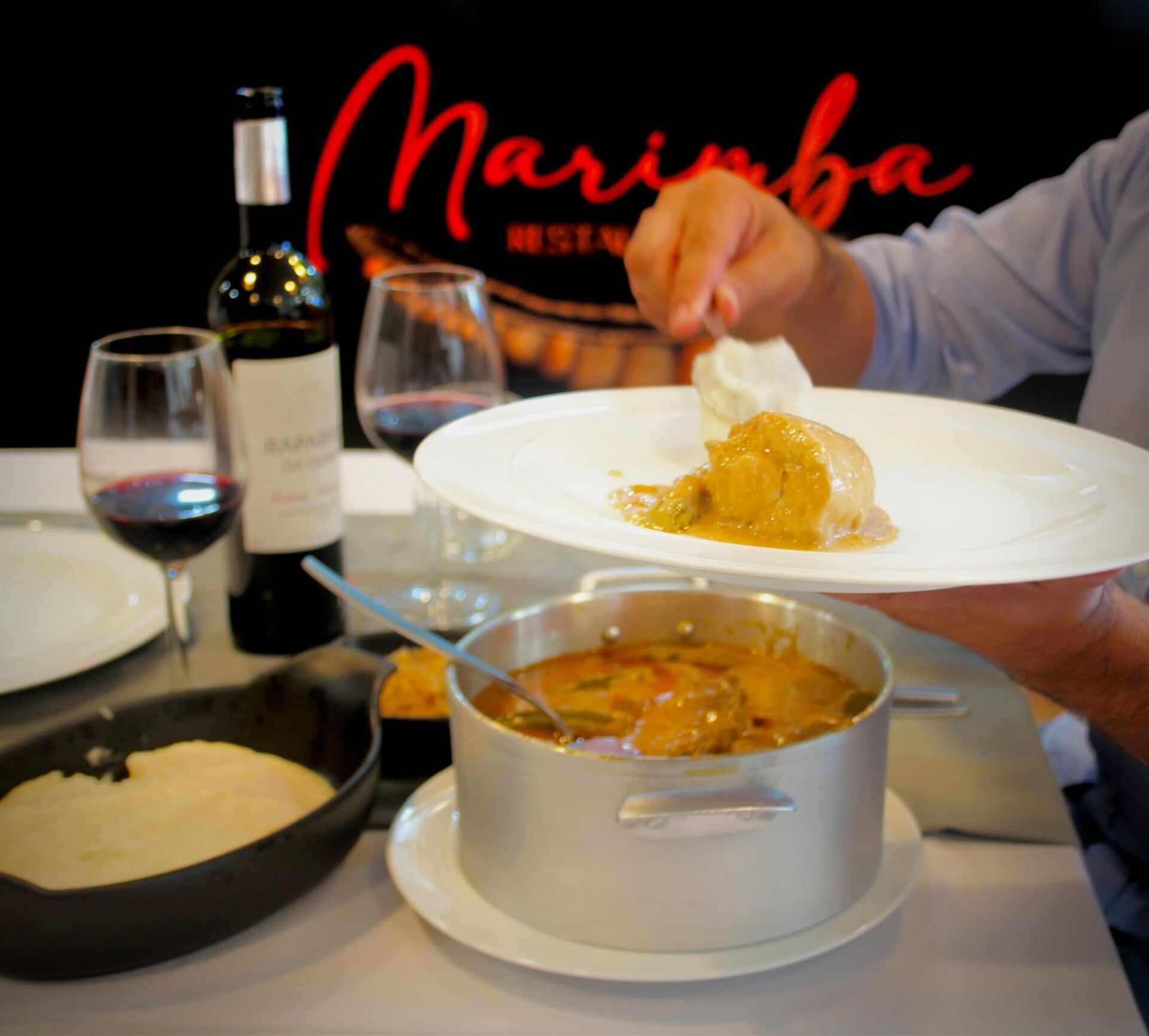 Uma pessoa segurando um prato de comida em frente a uma placa que diz marimba