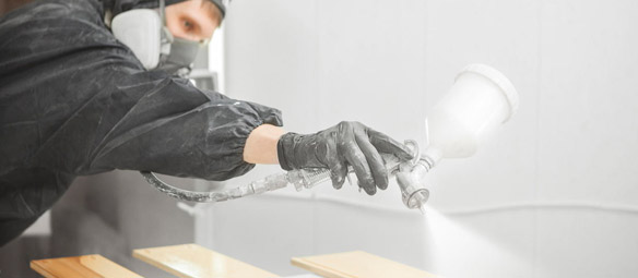 Una persona está rociando pintura sobre un trozo de madera.