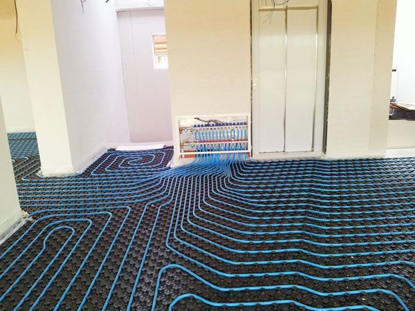 Una habitación con un laberinto de tuberías en el suelo y un ascensor al fondo.